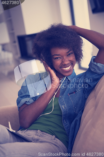 Image of African american woman at home in chair with tablet and head pho