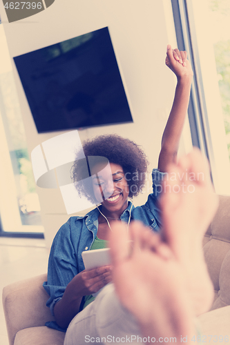 Image of African american woman at home in chair with tablet and head pho