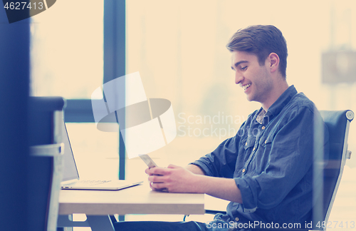 Image of Young casual businessman using smartphone