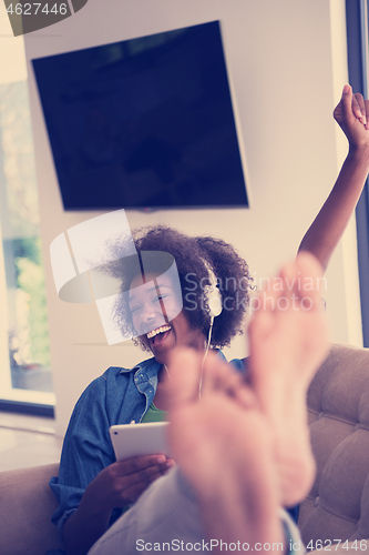 Image of African american woman at home in chair with tablet and head pho