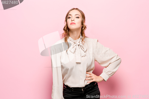 Image of The serious frustrated young beautiful business woman on pink background