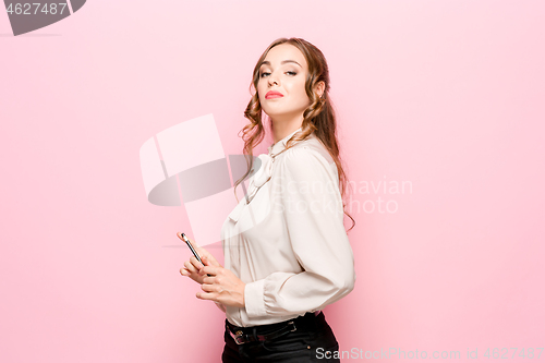 Image of The serious frustrated young beautiful business woman on pink background