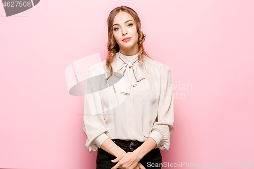 Image of The serious frustrated young beautiful business woman on pink background