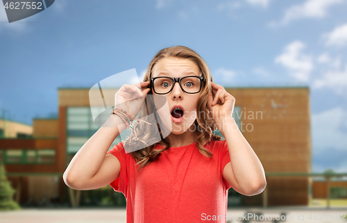 Image of surprised teenage girl in glasses over school