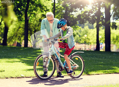 Image of grandfather and boy with bicycle at summer park