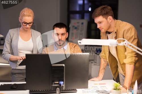 Image of business team with computer working late at office