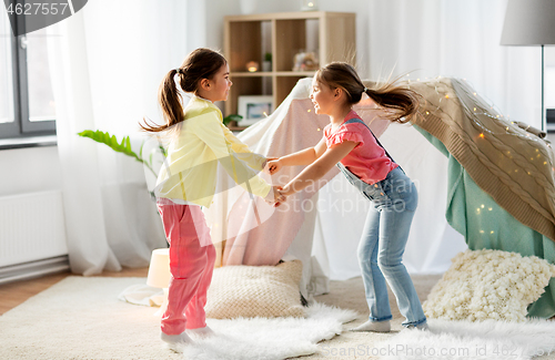 Image of happy girls playing near kids tent at home