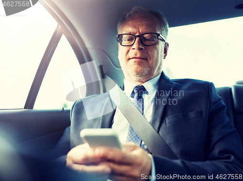 Image of senior businessman texting on smartphone in car