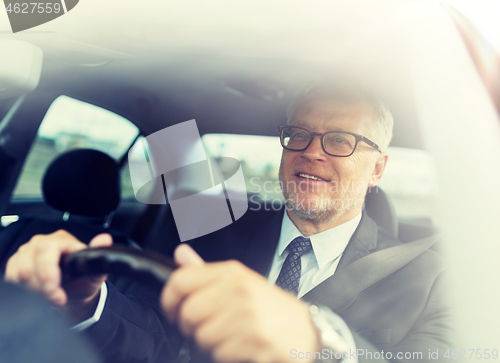 Image of happy senior businessman driving car