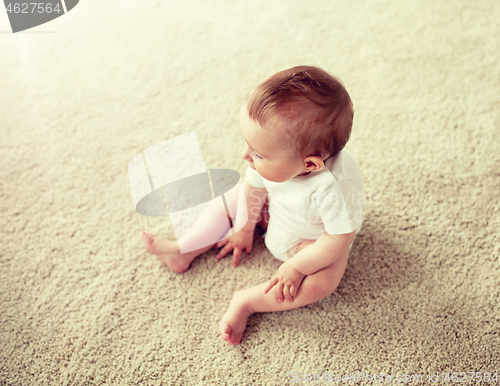 Image of happy baby boy or girl sitting on floor at home