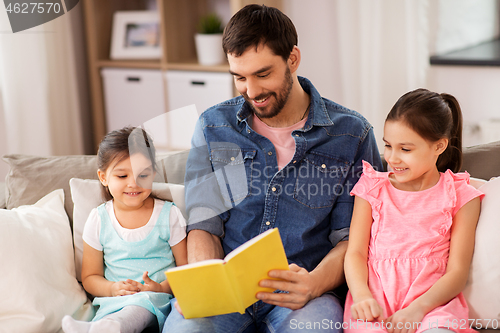 Image of happy father with daughters reading book at home