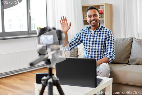 Image of male blogger with camera videoblogging at home