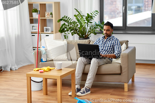 Image of man with laptop computer after home cleaning