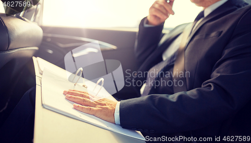 Image of senior businessman with papers driving in car