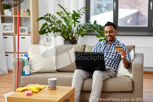 Image of man with laptop shopping online after cleaning