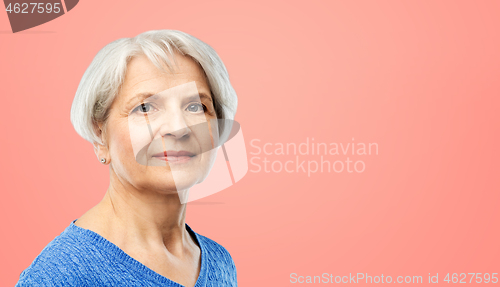 Image of portrait of senior woman in blue sweater over pink