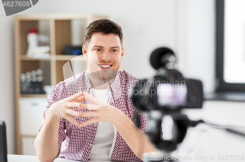 Image of male blogger with camera videoblogging at home