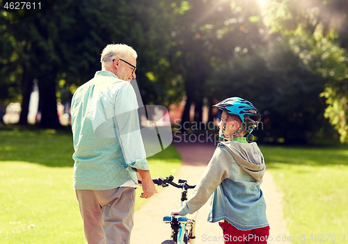 Image of grandfather and boy with bicycle at summer park