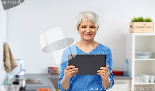 Image of senior woman using tablet computer at kitchen