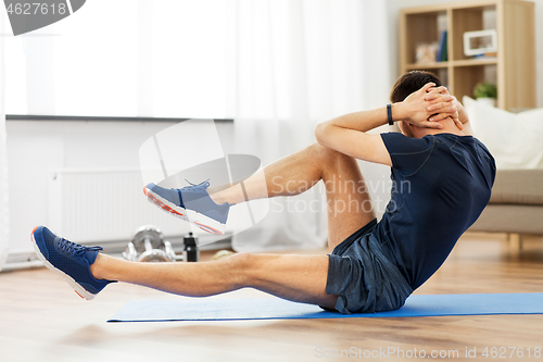 Image of man making bicycle crunch exercise at home