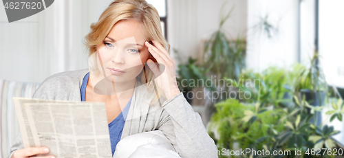 Image of woman reading newspaper at home