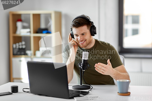 Image of man with laptop and microphone at home office