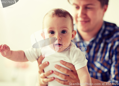 Image of happy young father with little baby at home