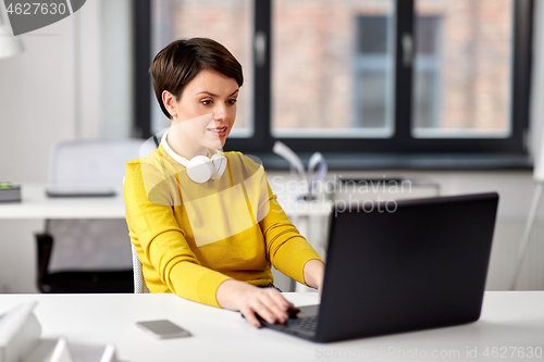 Image of happy businesswoman with laptop working at office