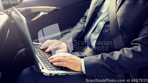 Image of senior businessman with laptop driving in car