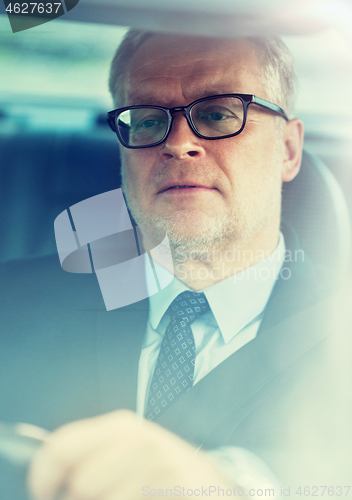 Image of senior businessman driving car