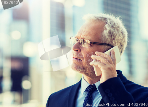 Image of senior businessman calling on smartphone in city