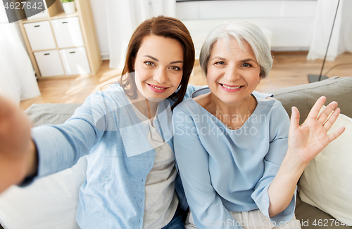 Image of senior mother and adult daughter taking selfie