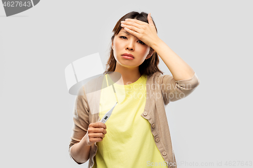 Image of sick asian woman with thermometer having fever