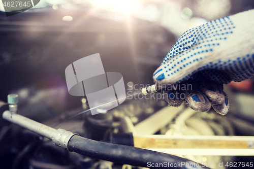 Image of mechanic with dipstick checking motor oil level