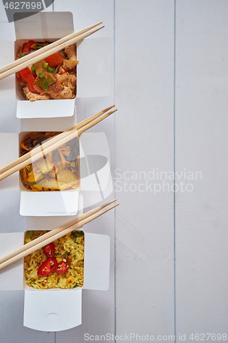 Image of Three take away paper boxes filled with asian food placed in row on white