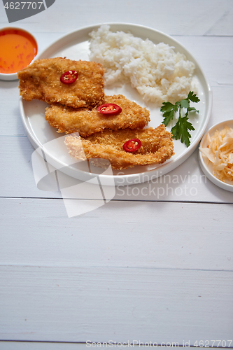 Image of Crispy chicken fried in breadcrumbs served with rice. View from the top on white wooden background