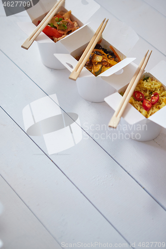 Image of Three take away paper boxes filled with asian food placed in row on white