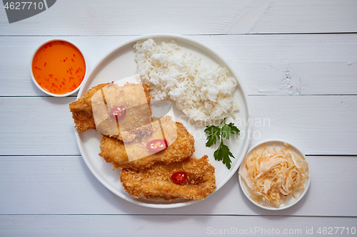 Image of Crispy chicken fried in breadcrumbs served with rice. View from the top on white wooden background