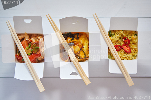 Image of Three take away paper boxes filled with asian food placed in row on white