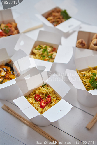 Image of Asian take away or delivery food concept. Paper boxes placed on white wooden table