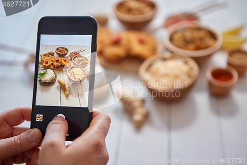 Image of Woman taking a photo with smartphone of deep fried Crispy chicken in breadcrumbs