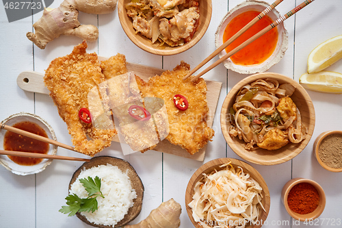 Image of Deep fried Crispy chicken in breadcrumbs served on white wooden table with salad, spices