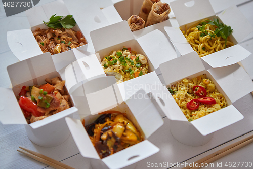 Image of Asian take away or delivery food concept. Paper boxes placed on white wooden table
