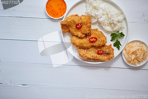 Image of Crispy chicken fried in breadcrumbs served with rice. View from the top on white wooden background