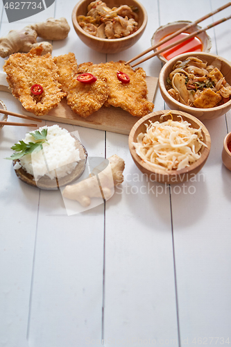 Image of Deep fried Crispy chicken in breadcrumbs served on white wooden table with salad, spices