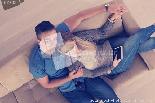 Image of youg couple in living room with tablet top view