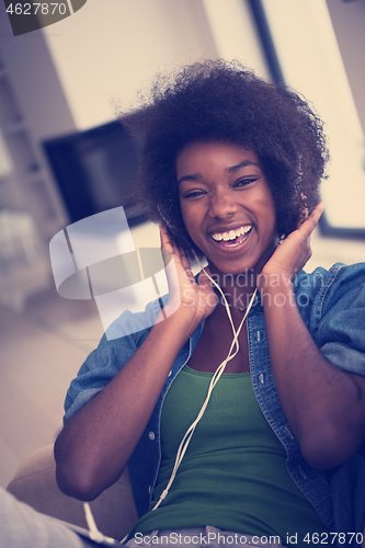 Image of African american woman at home in chair with tablet and head pho