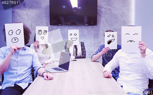 Image of startup business team holding a white paper over face