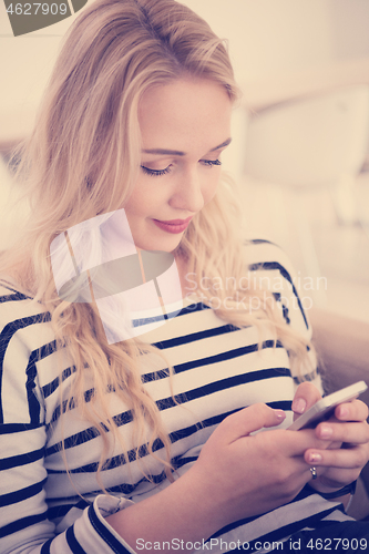 Image of woman sitting on sofa with mobile phone