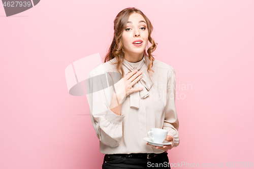 Image of The serious frustrated young beautiful business woman on pink background